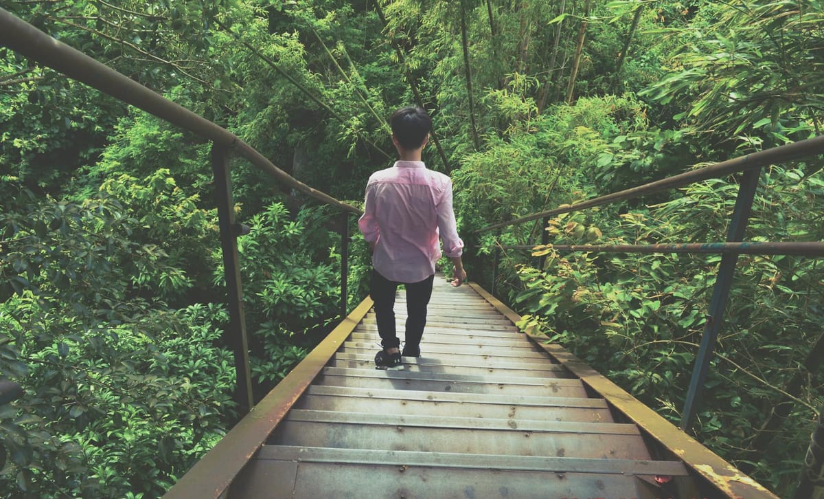 man wearing pink dress shirt walking through stairs